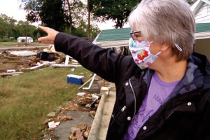Debra Ashton points to damage in her front yard that marks the area where she was swept away by the flood waters