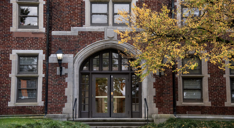 Photo of Morgan Hall during the fall, with yellow leaves on the tree by the front door