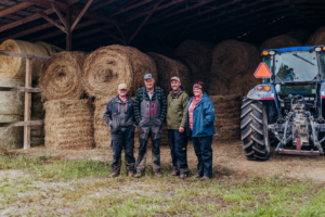 Family members standing on the Neely family farm with hay and a tractor
