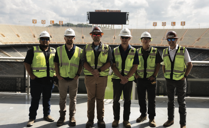 Construction science graduates standing in front of Neyland stadium
