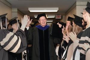 Jim Thompson high-fiving students at graduation