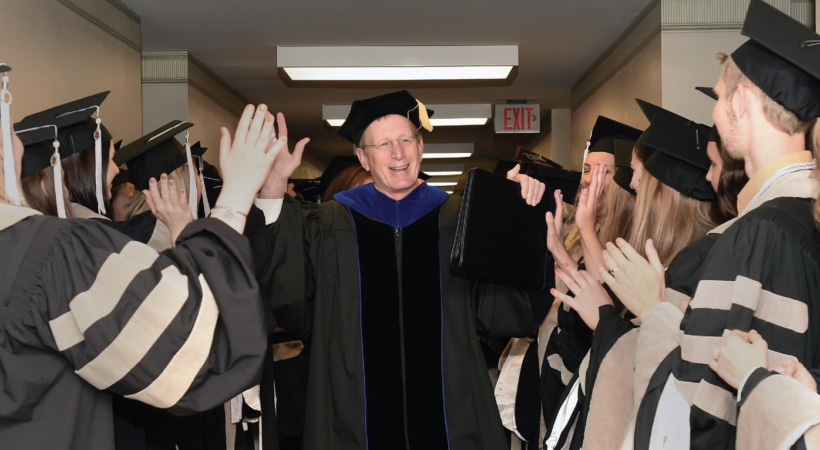 Jim Thompson high-fiving students at graduation