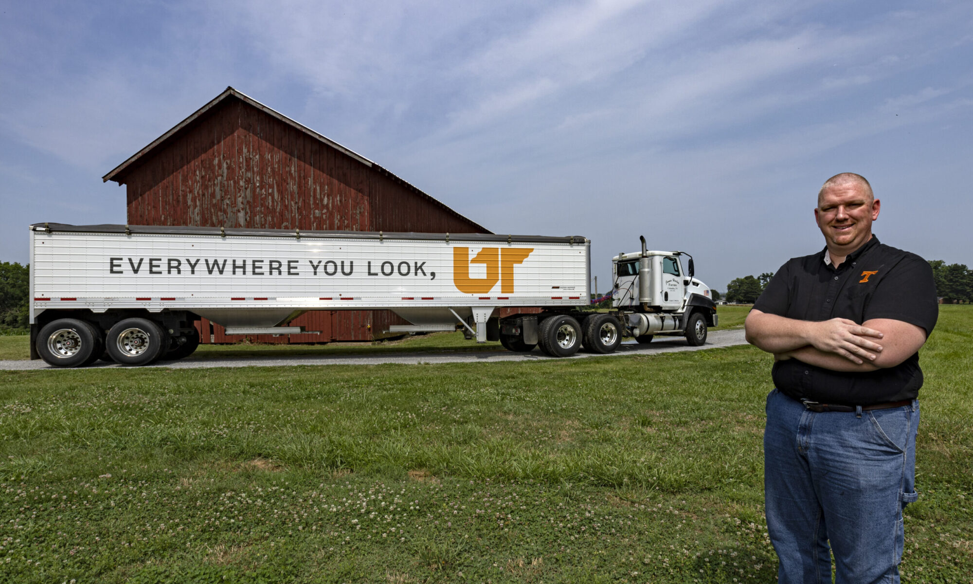 James Harlan standing in front of a grain trailer painted with "Everywhere You Look, UT"