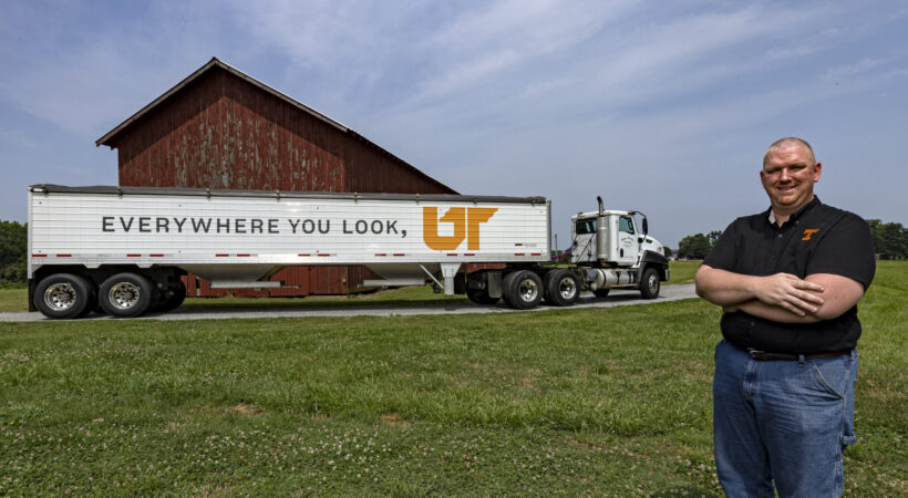 James Harlan standing in front of a grain trailer painted with "Everywhere You Look, UT"