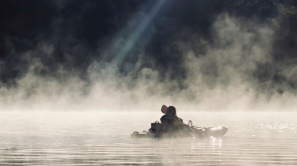 A person paddling on the river with fog