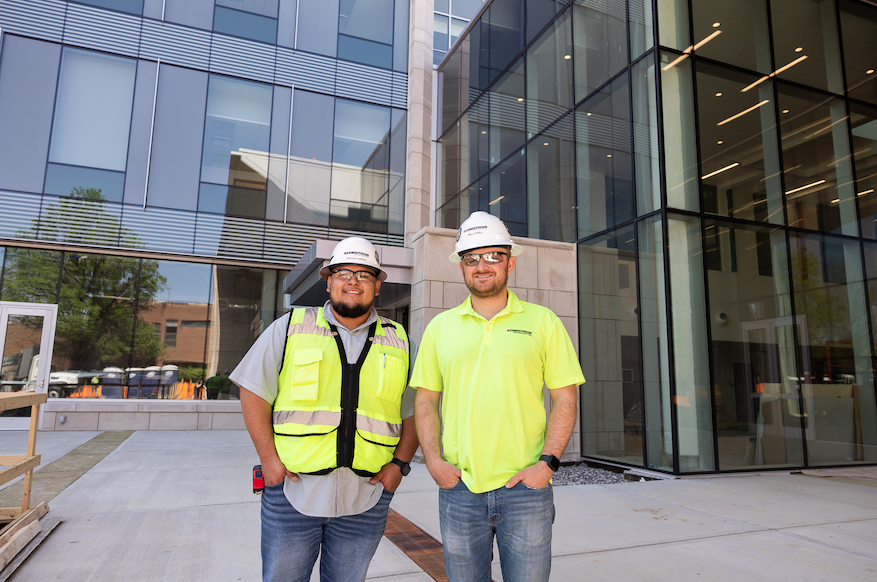 Two UT construction science graduates standing in front of the new building