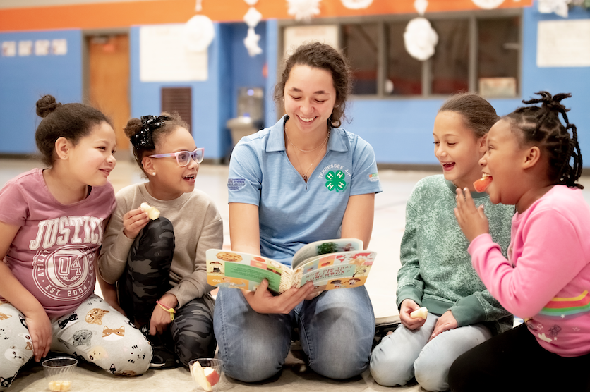 Katie Collins reading a book to four children