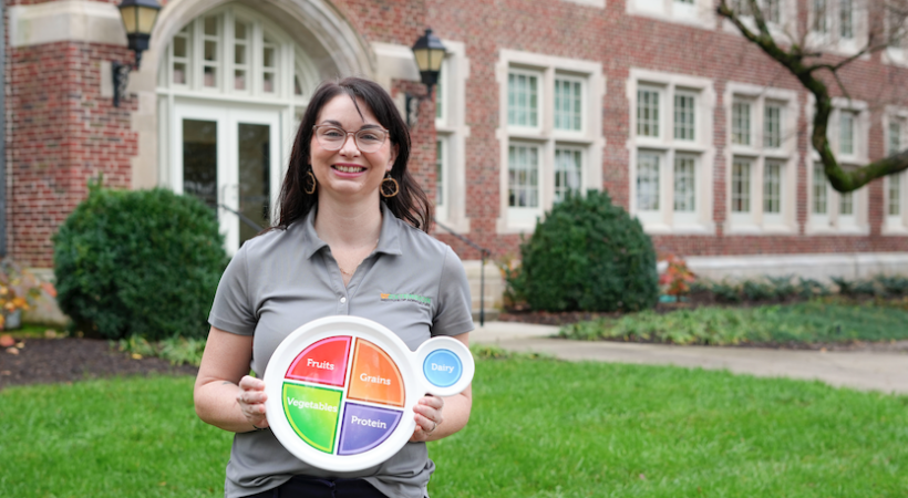 Kristin Riggsbee holding up a healthy plate in front of Morgan Hall