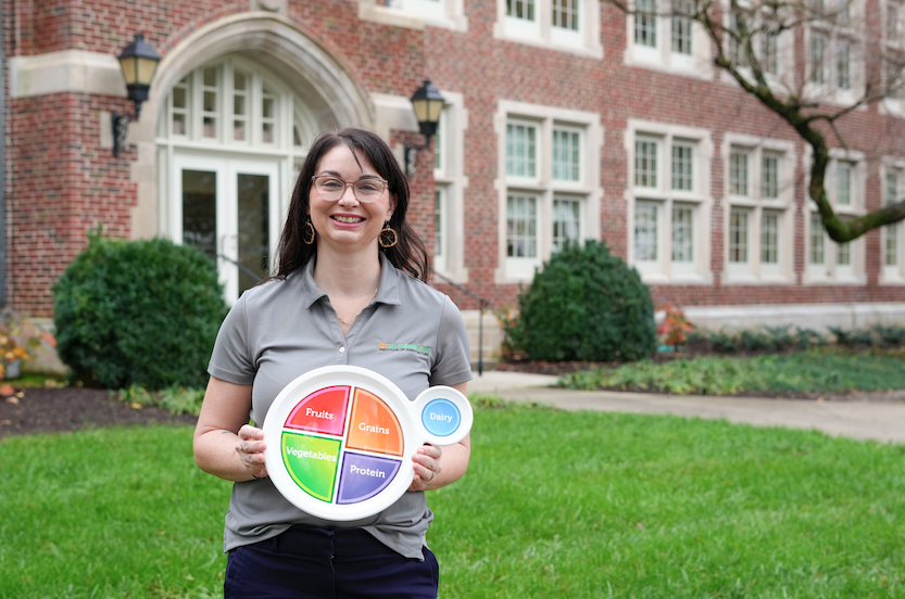 Kristin Riggsbee holding up a healthy plate in front of Morgan Hall