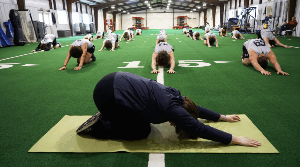 A person teaching yoga to a football team