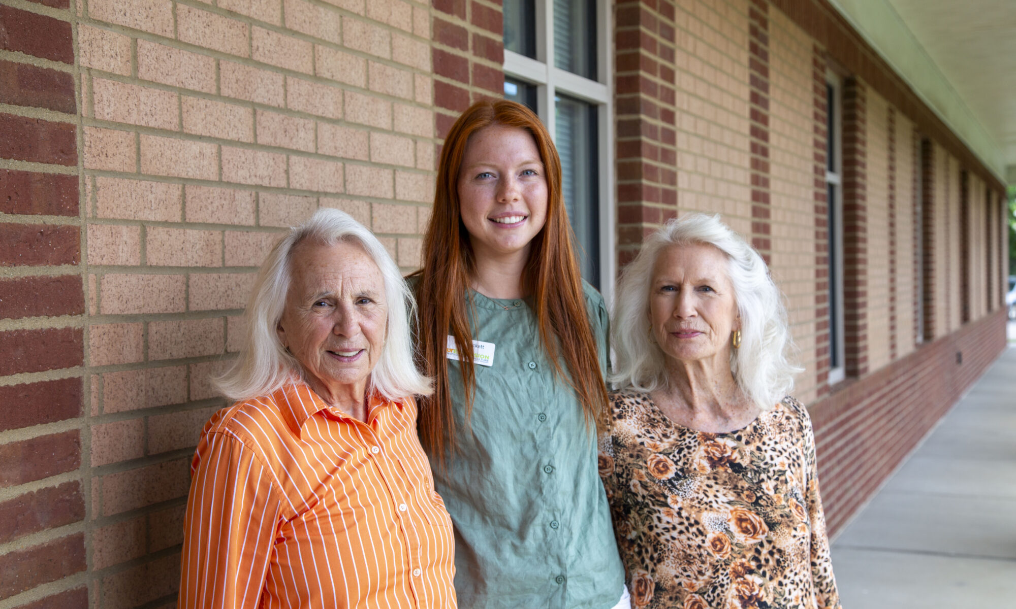 Three people posing for a photo in front of a brick building