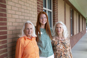 Three people posing for a photo in front of a brick building