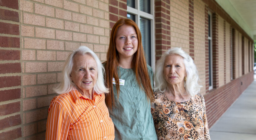Three people posing for a photo in front of a brick building