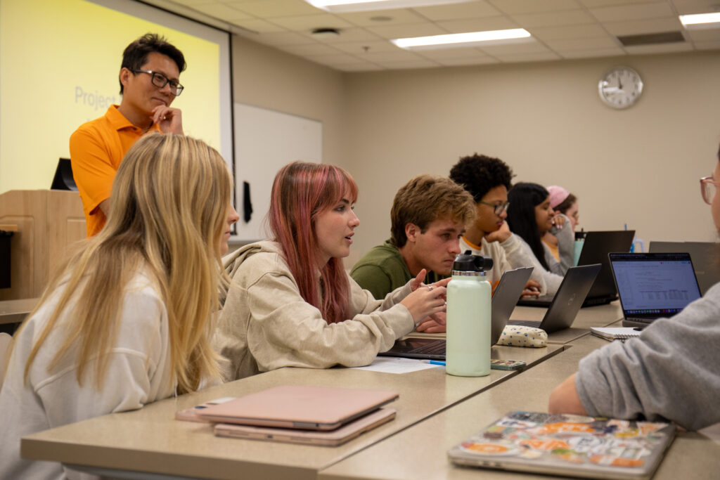 A professor listening to students while they work on an activity.
