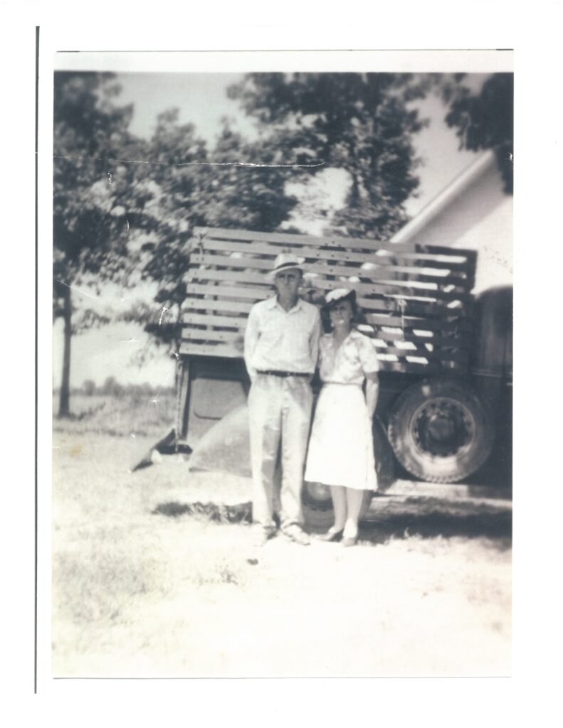 A couple standing in front of a truck.