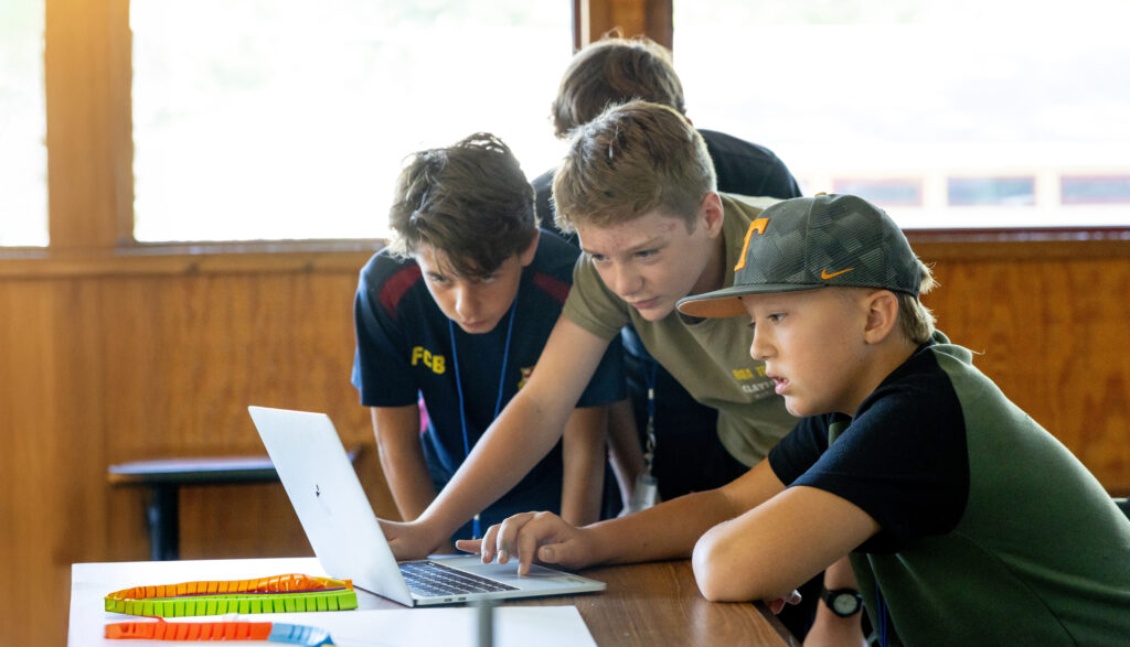 Four students in 4-H looking at a computer doing an activity to learn about smart technologies in farming