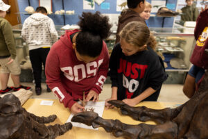 Two students examine similarities between a modern turkey’s foot and the bone structure of a Tyrannosaurus rex in the fossils classroom at the Clyde Austin 4-H Center in Greeneville, Tennessee.