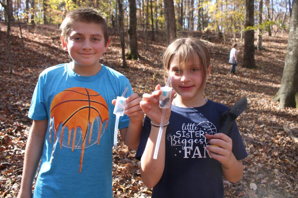 Youth hold up arthropods they captured using an aspirator device that allows close inspection and then gentle release.