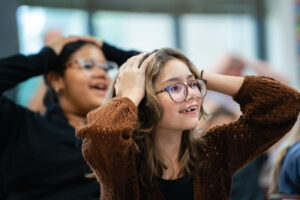 Two students with their hands on their heads engaged in a STEM activity