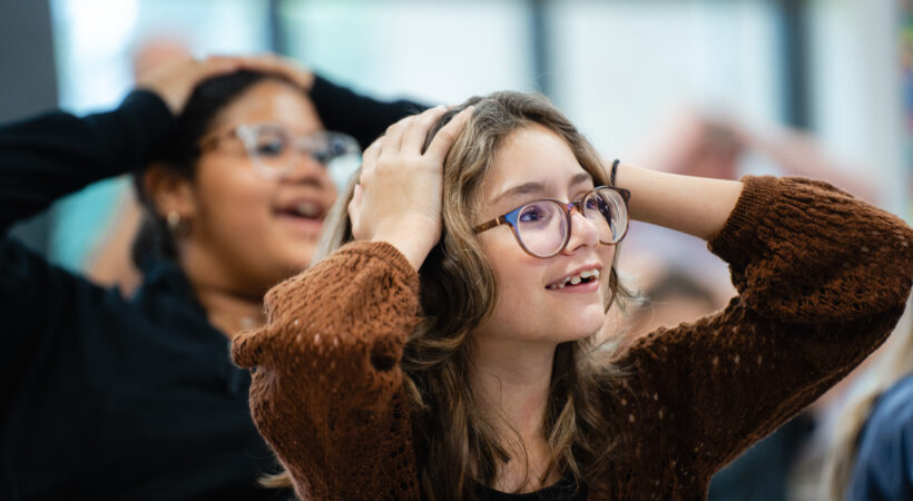 Two students with their hands on their heads engaged in a STEM activity