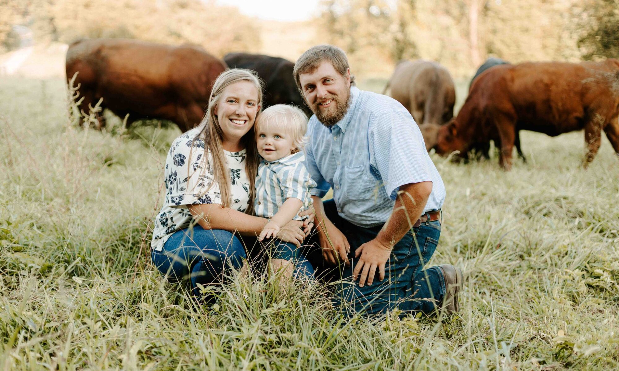 Alyssa Clements, her son, and her husband Adam Boucher posing in a field with cows